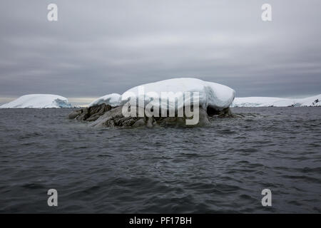 icecaps in the Antarctica with iceberg in the ocean swimming around and melting in the sea Stock Photo