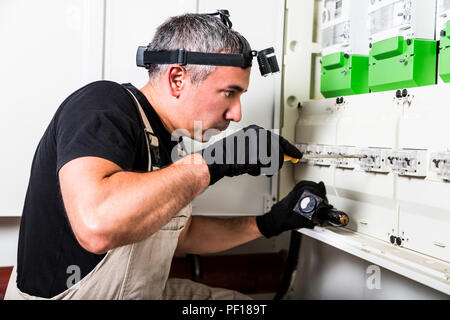 Electrician repairs and measures fuse box or switch box Stock Photo