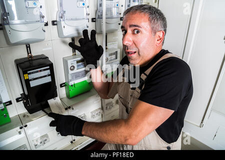 Funny electrician doing repair in switchboard or electricity meter Stock Photo