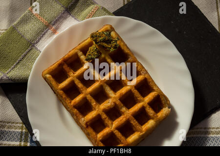 Sweet waffle with some marijuana buds. Weed and sweets, way to avoid munchies, perfect food for after smoking. Fight the hunger of smoking marijuana. Stock Photo