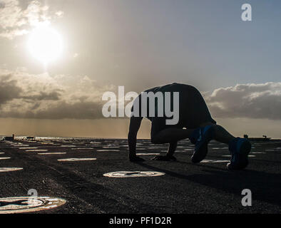 160222-N-VS214-184 PACIFIC OCEAN (Feb. 22, 2016) Hull Technician 1st Class Joe McClain works out at sunset on the flight deck of dock landing ship USS Harpers Ferry (LSD 49). More than 4,500 Sailors and Marines from Boxer Amphibious Ready Group and the 13th Marine Expeditionary Unit (13th MEU) are conducting sustainment training off the coast of Hawaii in preparation for entering the U.S. 5th and 7th Fleet areas of operations. (U.S. Navy photo by Mass Communications Specialist 3rd Class Zachary Eshleman/Released) Stock Photo