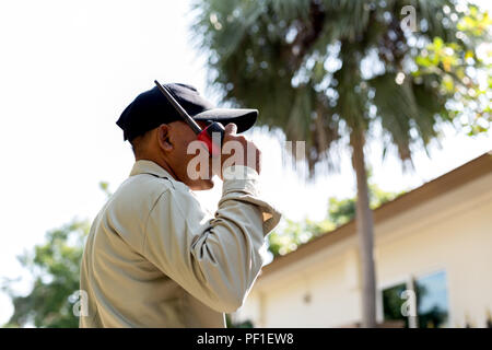 Male Security Guard talking on portable radio in village Stock Photo