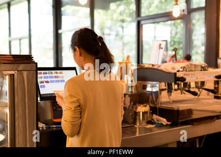 Woman at the cash register takes orders and bills using modern c Stock Photo