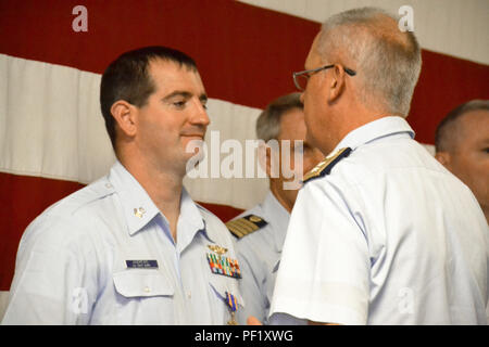 Rear Adm. Scott Buschman, commander Coast Guard Seventh District, Miami, presents an Air Medal to Petty Officer 2nd Class Joshua Andrews, a flight mechanic at Air Station Clearwater, Fla., during an awards ceremony at the station Feb. 24, 2016. Andrews was commended for his performance in saving 12 lives during Hurricane Joaquin. (U.S. Coast Guard photo by Auxiliarist Joe Perez) Stock Photo