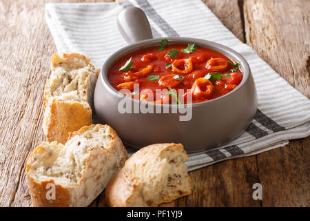Portion of squid with tomatoes served with fresh ciabatta close-up on the table. horizontal Stock Photo
