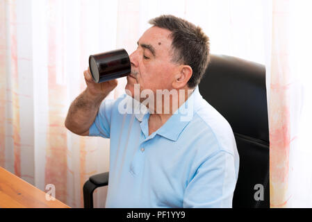 Senior man having a coffee and working on his computer Stock Photo