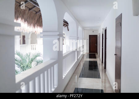 Contemporary white architecture, walkway and balcony in a luxury hotel in Mexico leading to a mahogany wooden door and room Stock Photo
