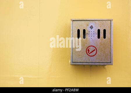 cigarette smokers steel metal ash tray fitted to yellow wall Stock Photo