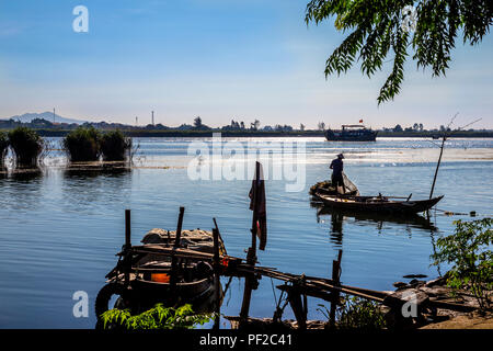 Scenic water view with fisherman getting his nets ready and a boat and islands off in the distance. Foregound has some rough dock and boat supplies. Stock Photo