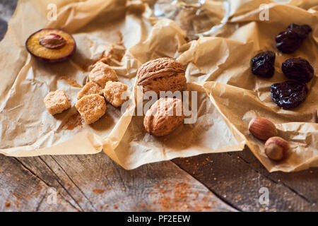 Dried plums, nuts, cinnamon and cane sugar on rustic background. Stock Photo