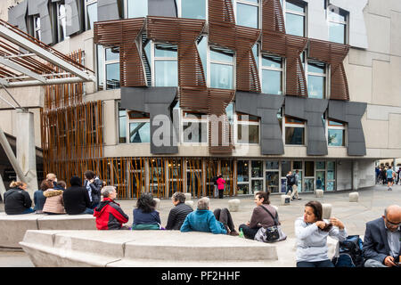 Tourists and visitors relaxing outside the Scottish Parliament building in Edinburgh, Scotland. Stock Photo