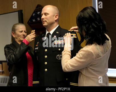 Mrs. Buschmann places a major rank on her husband, Maj. Denys Buschmann, Task Force 76, 76th Operational Response Command, operation officer, during a promotion ceremony at Fort Douglas, Utah, Feb. 27.  Maj. Gen. Ricky Waddell, 76th Operational Response Command commanding general presided over the ceremony. Stock Photo