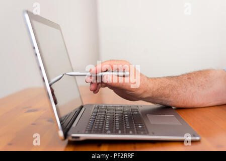 Close up of male senior hand pointing at laptop screen. Stock Photo