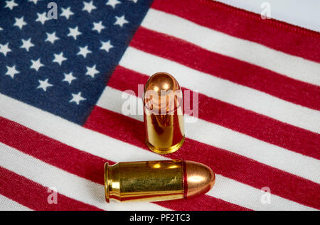 Two .45 caliber bullets laying on an American Flag Stock Photo