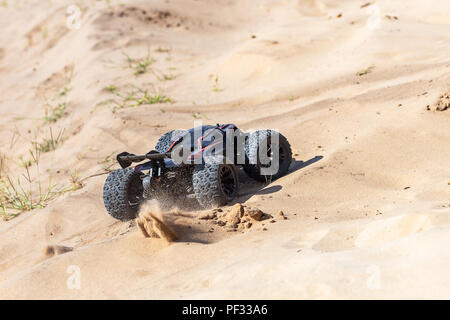 Big radio controlled buggy car driving fast and slipping on sand. RC toy moving fast on cross-terrain surface with dust and mud outdoors. Children hobby concept Stock Photo