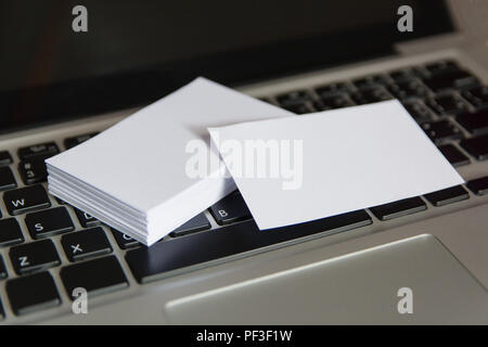 Stack of blank white business cards. Mockup business cards on keyboard laptop Stock Photo