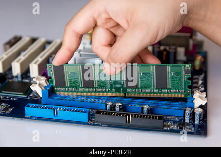 Technician installing RAM stick (random access memory) to socket on motherboard Stock Photo
