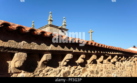 View of the Romanesque cornice corbels (cachorrada) with humans, animals and beasts grotesque figures carved in granite stone, in the historic village Stock Photo