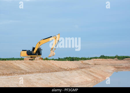 Yellow excavator machine working earth moving works riverside at construction site Stock Photo