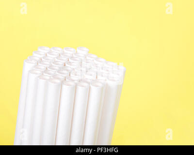 Dozens of biodegradable eco-friendly paper straws bundled together facing forward and upwards on a yellow background with copy space. Many cities are  Stock Photo