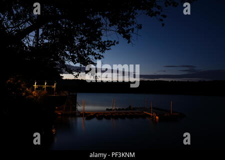 View of the park's boathouse during early morning twilight, with the dock illuminated by the lights at Lake Johnson Park in Raleigh North Carolina Stock Photo