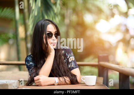 Women sit and wait at wooden tables in the garden. Stock Photo