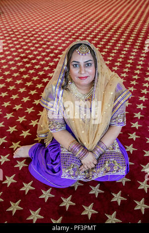 Posed portrait of a wedding guest seated in the temple at a wedding at the Gurdwara Sikh Cultural Society in Richmond Hill, Queens, New York City. Stock Photo