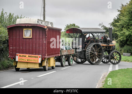 A Traction Engine tows a caravan as dozens of steam powered vehicles make their way through Dorset to the Great Dorset Steam Fair, where hundreds of period steam traction engines and heavy mechanical equipment from all eras gather for the annual show on 23 to 27 August 2018, to celebrate 50 years. Stock Photo