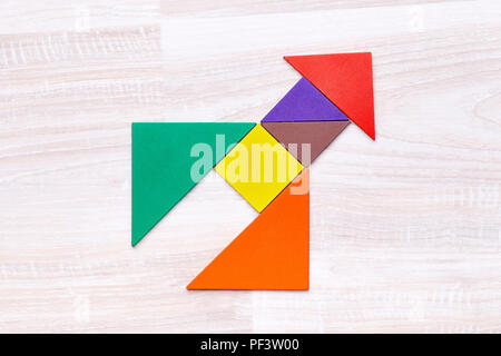 From above tangram figures into shape of rocket on wooden table in the center Stock Photo