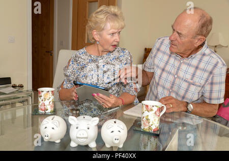 Elderly couple checking their expenditure and savings, Using Piggy Bank for an excess cash. Stock Photo