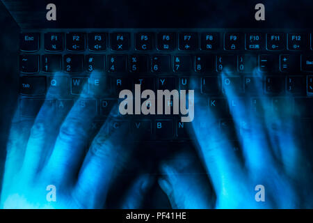 hands are typing on the keyboard in the dark. Blured Stock Photo