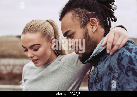 Young woman in sportswear standing with her arm around her boyfriend while taking a break from an outdoor run together Stock Photo