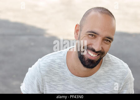 Portrait of a spanish man with beard smiling looking camera, wearing a snapback hat and a t-shirt, outdoors. Stock Photo