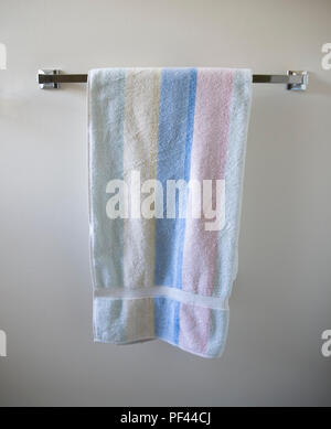 striped towel hanging from a silver towel rack on a white wall Stock Photo