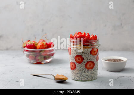 healthy breakfast. overnight oatmeal with strawberries, chia seeds in a glass jar on a gray background Stock Photo