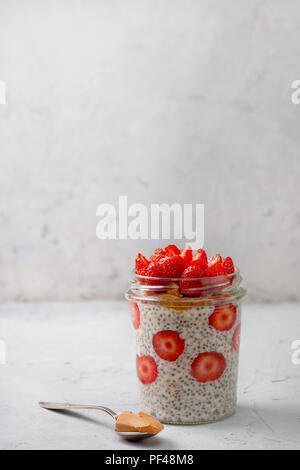 healthy breakfast. overnight oatmeal with strawberries, chia seeds in a glass jar on a gray background Stock Photo