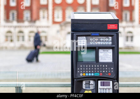 Car park ticket machine on a London street with an unidentified traveller in the background Stock Photo