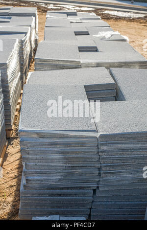 Stacks of paving slabs stacked in piles over wooden pallets at construction site. Closeup Stock Photo