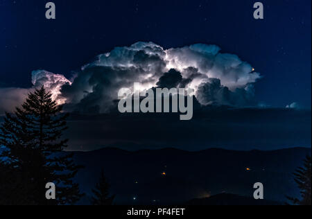 A huge thunderstorm with active lightning lighting up the clouds is seen from the high peak of Spruce Knob in the Appalachian Mountains of West Virgin Stock Photo
