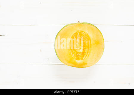 One half of fresh melon cantaloupe variety flatlay on grey wood Stock Photo