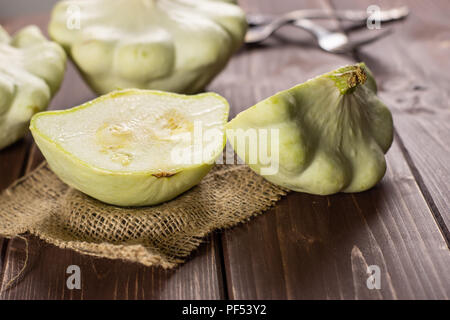 Group of two whole two halves of summer white pattypan squash composition on linen cloth on brown wood Stock Photo