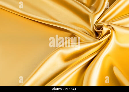 Smooth elegant golden silk or satin luxury cloth. Luxurious background design. golden silk wavy background Stock Photo