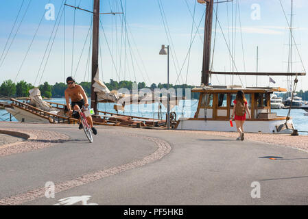 Helsinki Finland summer, view on a summer morning of a young man on a bike cycling on a cycle path along the quayside in Helsinki harbor, Finland. Stock Photo