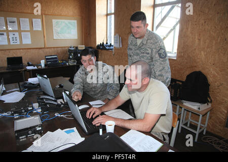 Capt. Matt Saccone, Master Sgt. Frank Hegedus and Master Sgt. Ken Supsic discuss briefing topics in the tactical operations center at Brig. Gen. Kazio Veverskis Training Grounds, Kazlu Ruda, Lithuania on Aug. 18, 2018. Members of the Pennsylvania Air National Guard are deployed for training to Lithuania to help construct an air-to-ground range used to train Lithuanian and NATO forces. Stock Photo