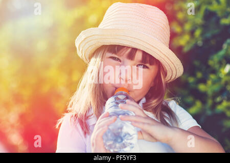 Cute little girl drinking water in summer Stock Photo