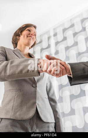Businesswoman shaking hands with a businessman , low angle view. Stock Photo