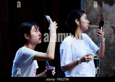 Two Asian women using their smartphones, Gracia, Barcelona, Spain. Stock Photo