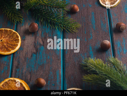 Christmas decoration on wooden rustic desk. Citrus dried slices, fir branches, and hazelnuts. Space for text. Stock Photo
