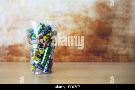 Old Empty Non Rechargeable Batteries Pilled up in Plastic Cup. Blurred Abstract Background. Very Low depth of the Field. Stock Photo