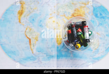 Empty Disposable Batteries pilled in Plastic Cap. Map of the World as Blurred Background. Low depth of the Filed. View from above. Stock Photo